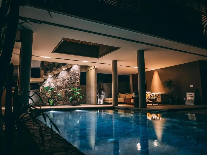 A covered pool between pillars at night