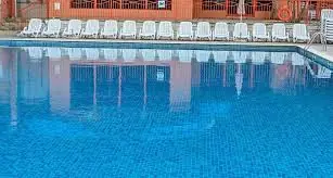 An outdoor public pool with rows of deck chairs