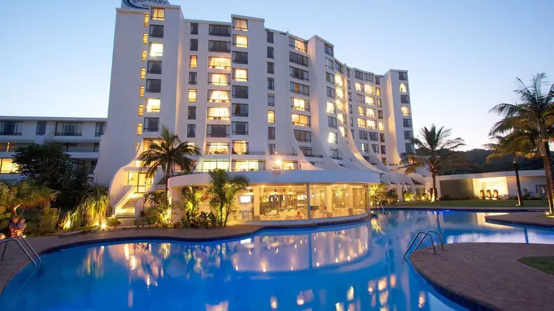 A resort pool below a hotel tower at dusk