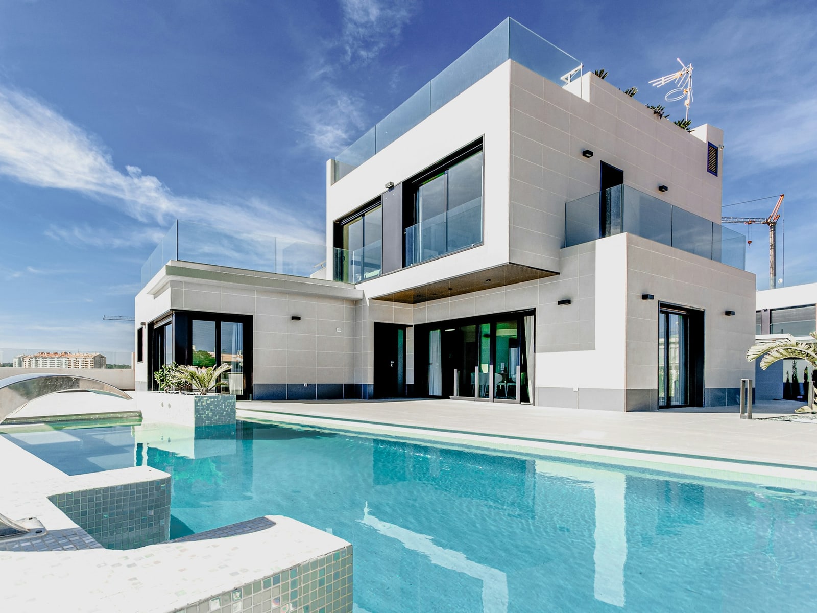 Crystal-clear pool beside a white contemporary house under a blue sky