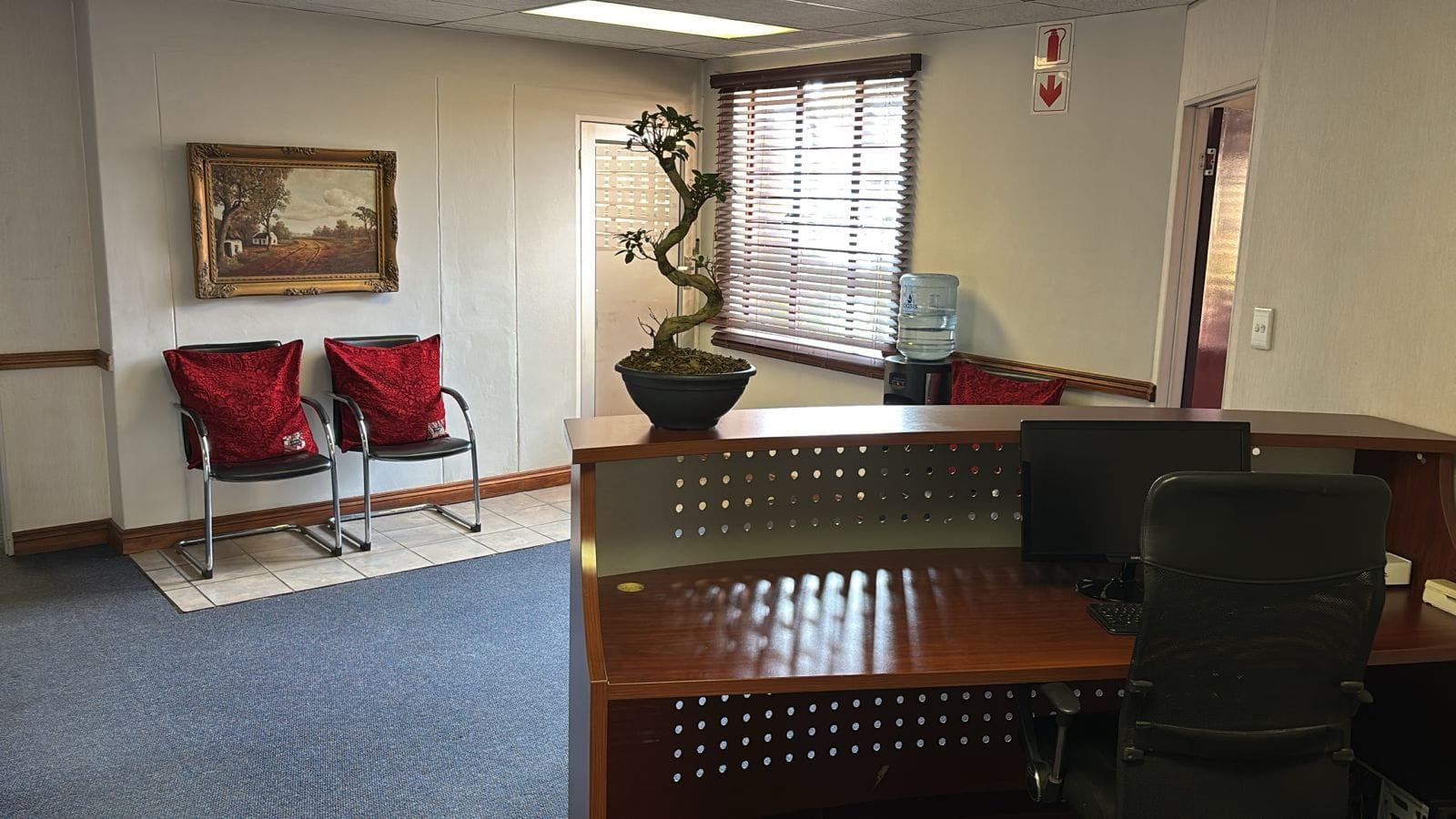 Reception desk seen from behind, with visitor chairs and a water cooler