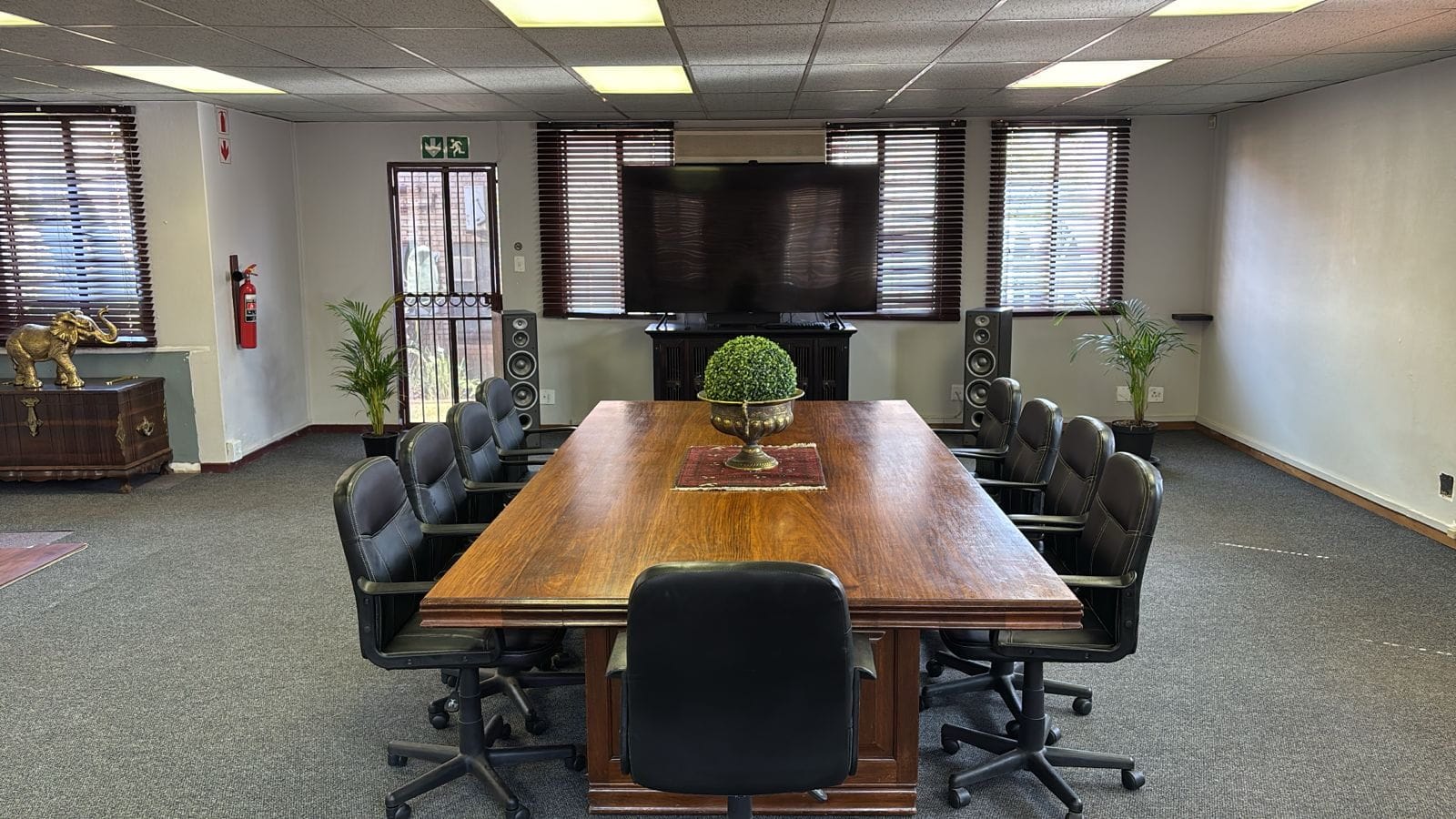 Boardroom with a long wooden table and a large wall-mounted presentation screen