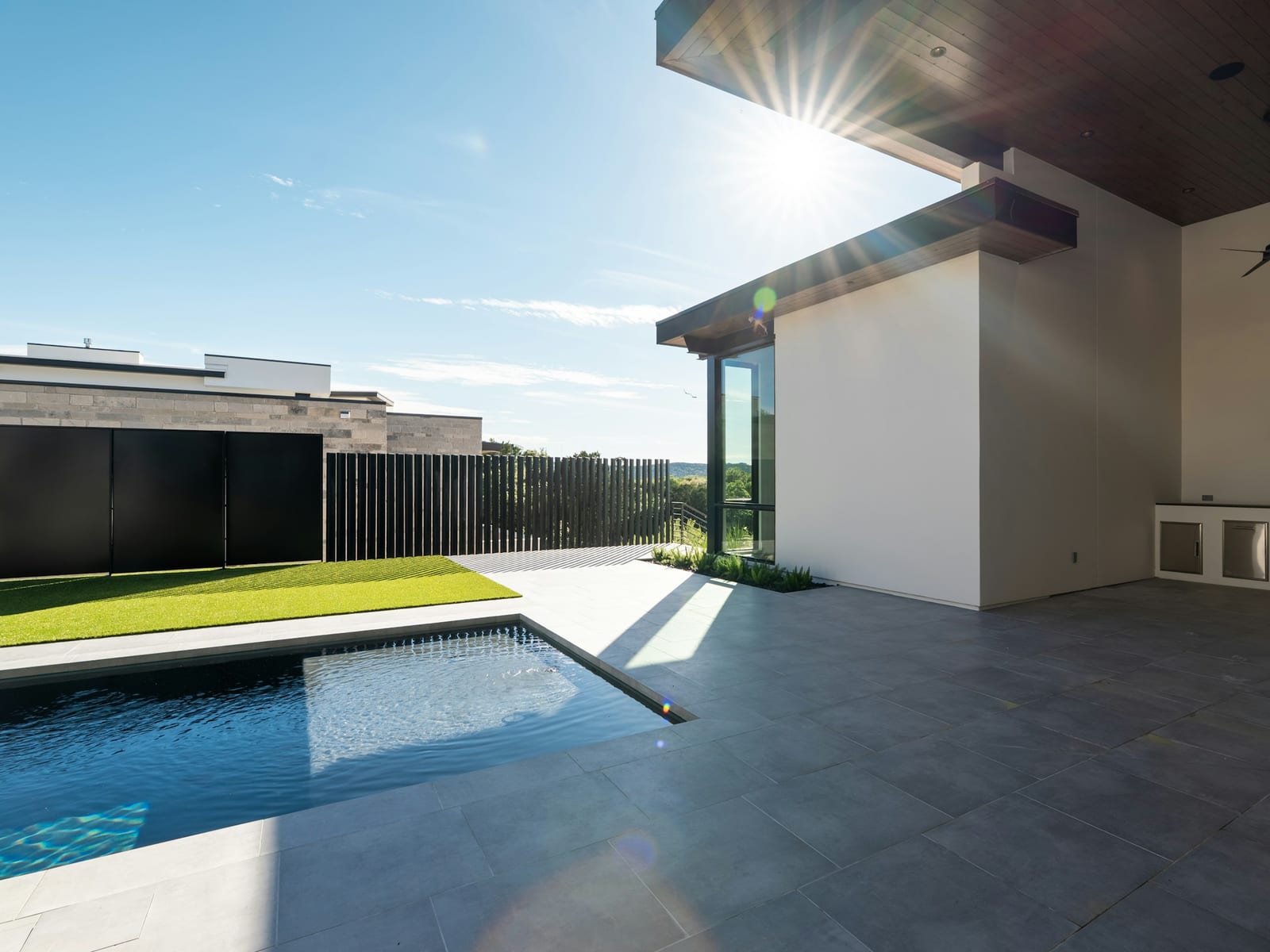 A covered patio with a built-in braai beside a dark-tiled pool